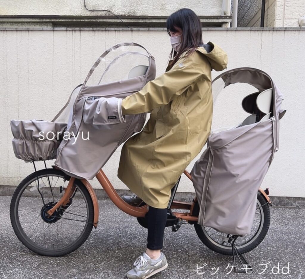 バイシカバーの高機能レインコートを着たママが雨対策した電動自転車に乗る